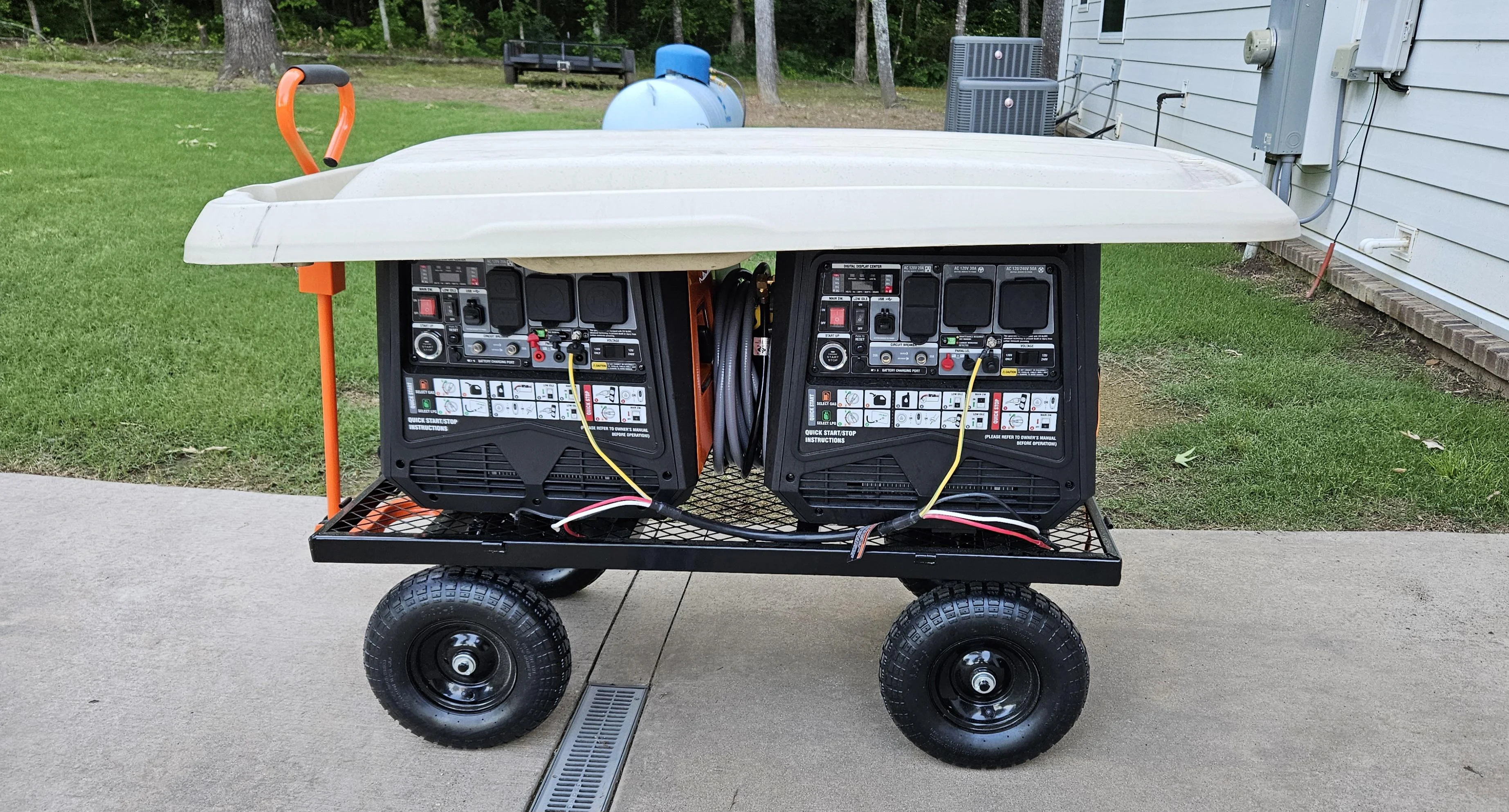 A portable generator running outdoors on a driveway away from open doors and windows with an extension cord leading toward a house